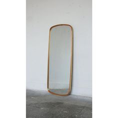 a gold framed mirror against a white wall in an empty room with concrete flooring