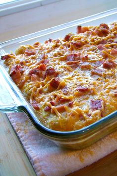 a casserole dish with bacon and cheese in it sitting on a wooden table