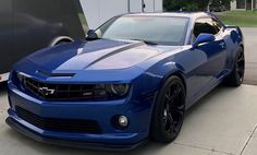 a blue chevrolet camaro parked in front of a trailer