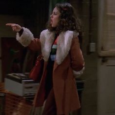 a woman in a brown coat pointing at something