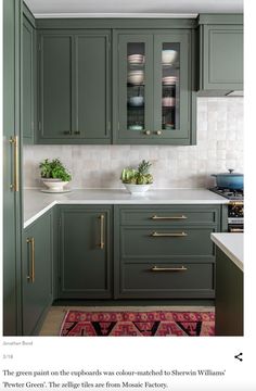 an image of a kitchen setting with green cabinets and white counter tops, gold trim