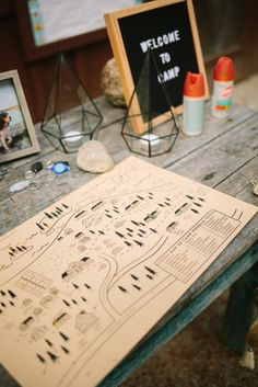 a wooden table topped with a map next to two framed pictures and other items on top of it