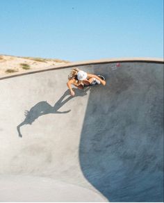 a person riding a skateboard up the side of a cement ramp at a skate park