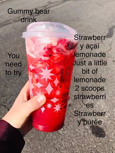 a person holding up a cup with strawberries and ice cream in it on the street