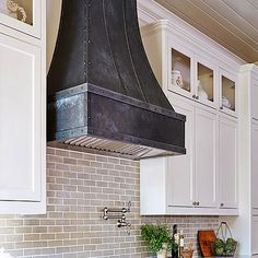 a stove top oven sitting inside of a kitchen next to white cabinets and counter tops