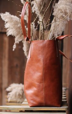 Simple, raw-finished leather bag in a minimalistic style. It is inconspicuous in size but has more than enough room to accommodate your whole world. The bag has a magnetic closure, a small pocket for your smartphone and other essentials, and rolled handle. The bag is both stable and ductile. With time it becomes softer and gets deeper character. The bag size measured in the position presented in the photo is: 35 cm (width), 38 cm (height), 18 cm (depth). When measured laid flat the width amounts Brown Minimalist Shoulder Bag With Leather Lining, Natural Leather Bucket Bag Tote, Natural Leather Bag Vegetable-tanned, Rectangular Natural Vegetable-tanned Shoulder Bag, Natural Leather Bucket Shoulder Bag, Daily Handmade Vegetable Tanned Leather Shoulder Bag, Modern Brown Vegetable-tanned Bag, Minimalist Leather Shoulder Bag, Vegetable-tanned, Minimalist Vegetable-tanned Leather Shoulder Bag