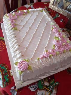 a large white cake sitting on top of a table covered in frosting and pink flowers