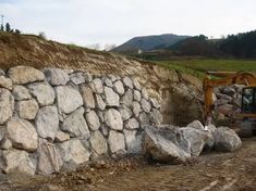 a bulldozer digging into a large pile of rocks next to a construction site