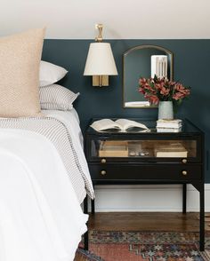 a bedroom with blue walls and white bedding has a black table with flowers on it