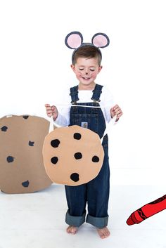 a little boy that is standing up with some kind of thing in his hand and wearing mouse ears