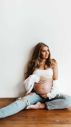 a pregnant woman is sitting on the floor with her belly wrapped up and looking at the camera