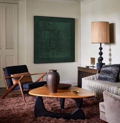 a living room filled with furniture and a painting hanging on the wall above it's coffee table