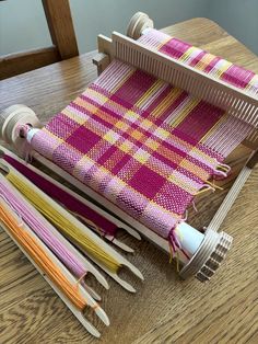 the loom is sitting on the table with several different colored yarns in it