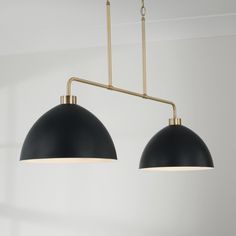 two black and gold pendant lights hanging from a ceiling fixture in a room with white walls