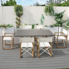 a table and chairs on a wooden deck with plants in the backgroung