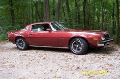 a red car is parked in the woods