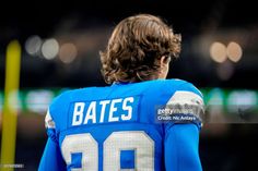 a close up of a football player with his back to the camera, wearing a blue jersey