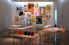 an art gallery with multiple tables and posters on the wall