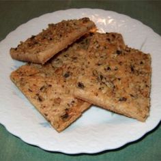 four pieces of crackers on a white plate with green tablecloth and blue background