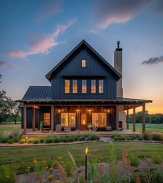 a large house with lots of windows and lights on it's front porch at dusk