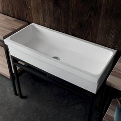 a white sink sitting on top of a wooden counter next to a vase and table