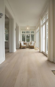 an empty living room with white furniture and large windows on both sides of the room