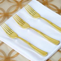 three forks and two knives are on a white napkin with gold circles in the background