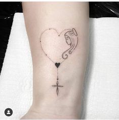 a small tattoo on the foot of a person with a cross and heart attached to it