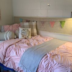 a bed with pink sheets and pillows on top of it in a room that has white brick walls