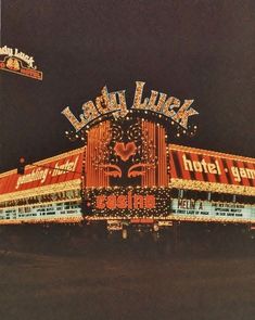 an old photo of a hotel sign lit up in the night time with lights on it