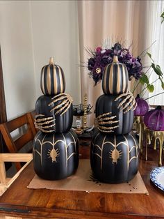 two black pumpkins sitting on top of a wooden table