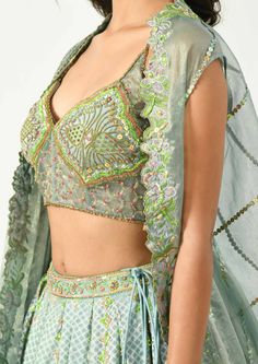 Go classy yet modern with this beautiful piece of attire. The grey-blue hued pleated lehenga has geometric and floral prints highlighted with hand and machine embroidery, the corset style blouse has multi colored sequins and beads to define the motifs, bringing an ethereal look. The key highlight, the cape has the cutwork at the border and pleats at one side making it look like a draped dupatta. Machine Embroidery Lehenga, Party Choli With Intricate Embroidery For Transitional Season, Designer Blue Party Sets, Designer Choli With Dupatta For Festivals, Designer Silk Choli For Festive Occasions, Designer Sets With Intricate Embroidery For Party, Fitted Embellished Multicolor Sharara, Designer Sequin Sets For Receptions, Fitted Multicolor Embellished Sharara