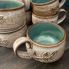 four coffee mugs sitting on top of a wooden table