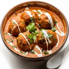 a bowl filled with meatballs covered in sauce and garnished with cilantro