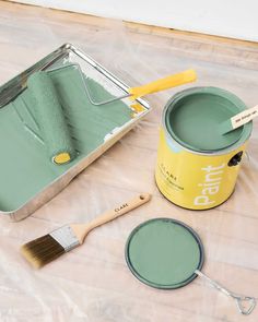 a paint can and brush sitting on the floor next to it's matching colors