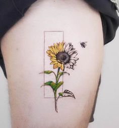 a sunflower tattoo on the back of a woman's left thigh, with a bee flying over it