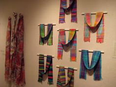 colorful scarves are hung on the wall next to each other in an art gallery