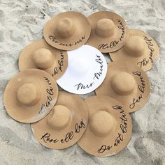 a group of brown hats sitting on top of a sandy beach covered in words and writing