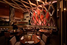 an empty restaurant with tables and chairs in front of a large red sculpture on the wall