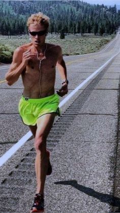 a shirtless man running down the road with no shirt on and headphones in his ears