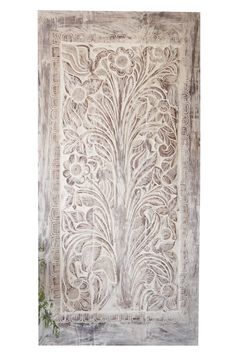 an old wall hanging on the side of a building with flowers and leaves painted on it