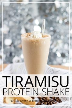 a glass filled with coffee and whipped cream on top of a wooden table next to nuts