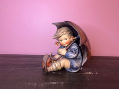 a figurine sitting on top of a wooden table next to a pink wall