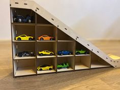 toy cars are lined up on shelves in the shape of a house that is made out of cardboard