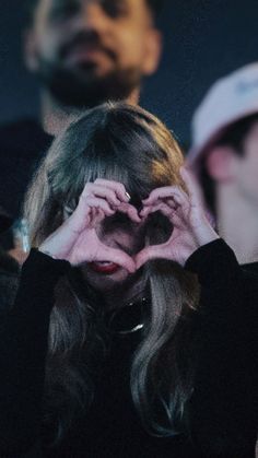 a woman holding her hands up to her face while looking through the holes in her heart