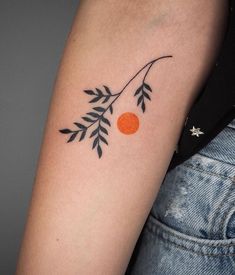 a woman's arm with an orange and black branch tattoo on the left upper arm