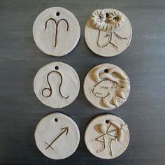 four clay ornaments with zodiac symbols on them