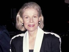 an older woman with blonde hair wearing a black jacket and white shawl smiling at the camera