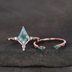 a ring with an aqua green stone and white diamonds on the side, sitting on top of a rock