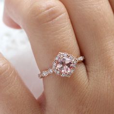 a woman's hand with a pink diamond ring on it